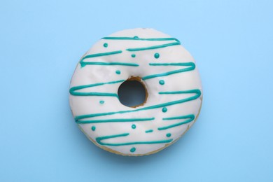 Tasty glazed donut on light blue background, top view