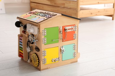 Photo of Busy board house on floor indoors. Baby sensory toy