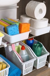 Photo of Open under sink cabinet with different cleaning supplies in kitchen