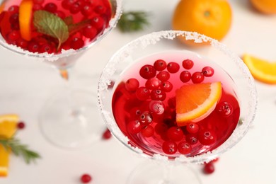 Tasty cranberry cocktail in glasses on white table, above view