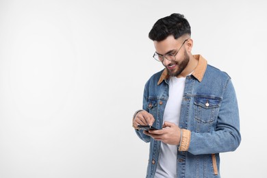 Happy young man using smartphone on white background, space for text