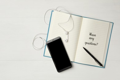 Photo of Notebook with phrase HAVE ANY QUESTIONS and smartphone on white wooden table, flat lay