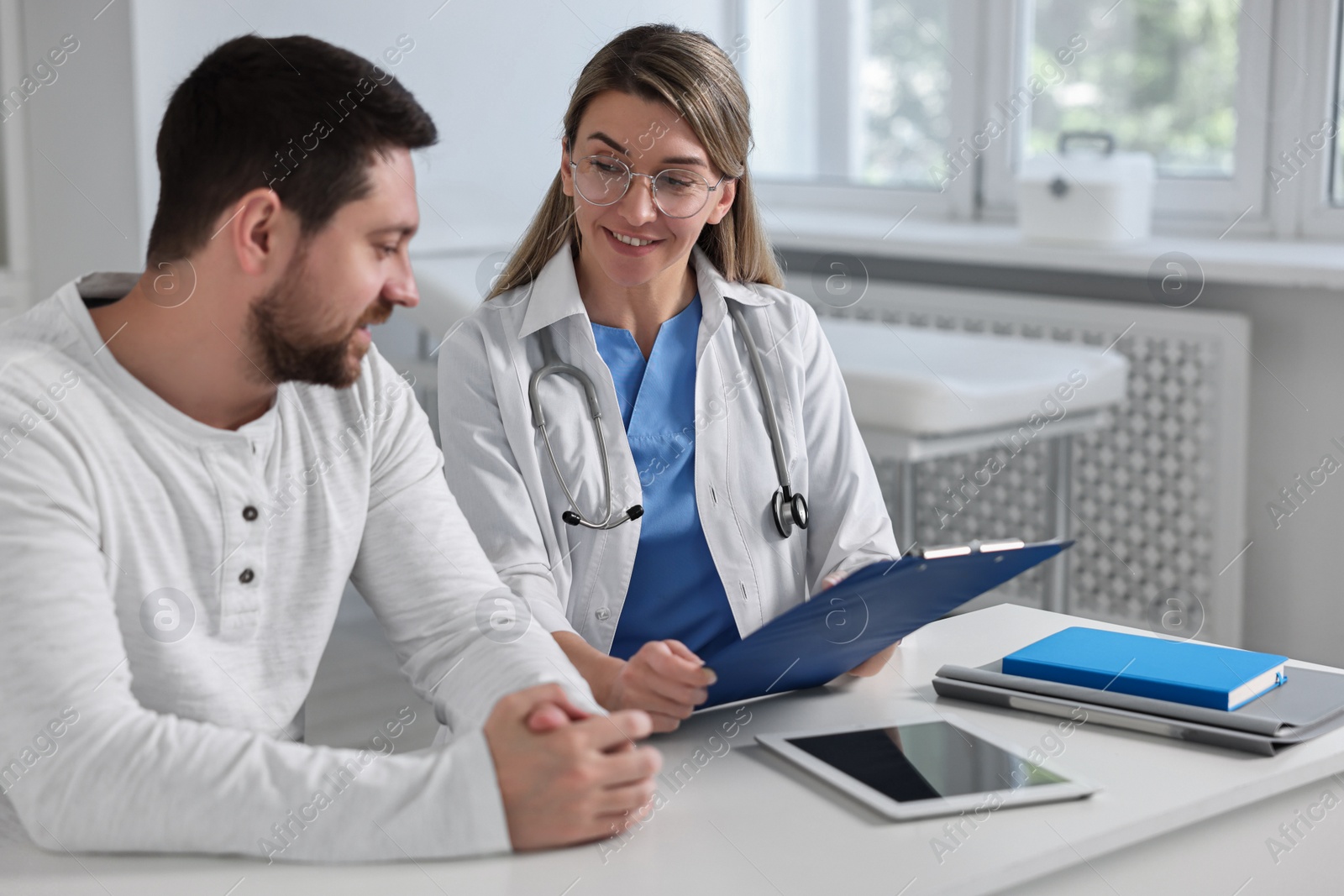 Photo of Professional doctor working with patient at white table in hospital