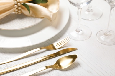 Photo of Golden cutlery and plates with napkin on wooden background, closeup. Festive table setting