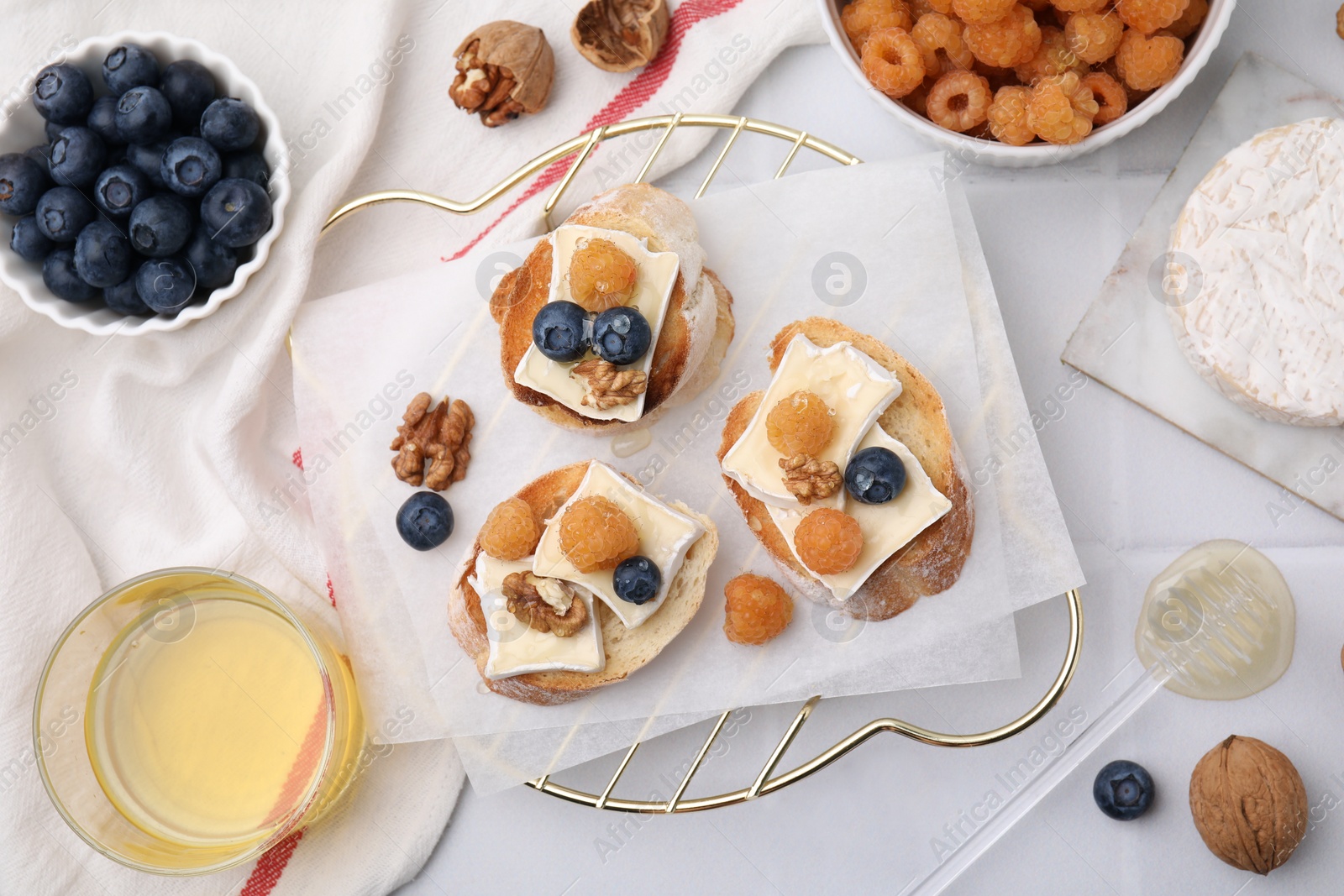 Photo of Tasty brie cheese sandwiches on white tiled table, flat lay