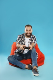 Photo of Emotional young man playing video games with controller on color background. Space for text