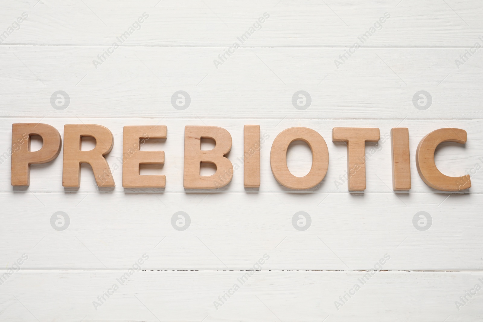 Photo of Word Prebiotic made of letters on white wooden table, top view
