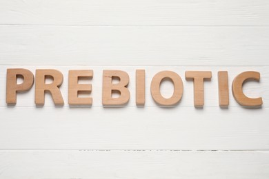 Photo of Word Prebiotic made of letters on white wooden table, top view