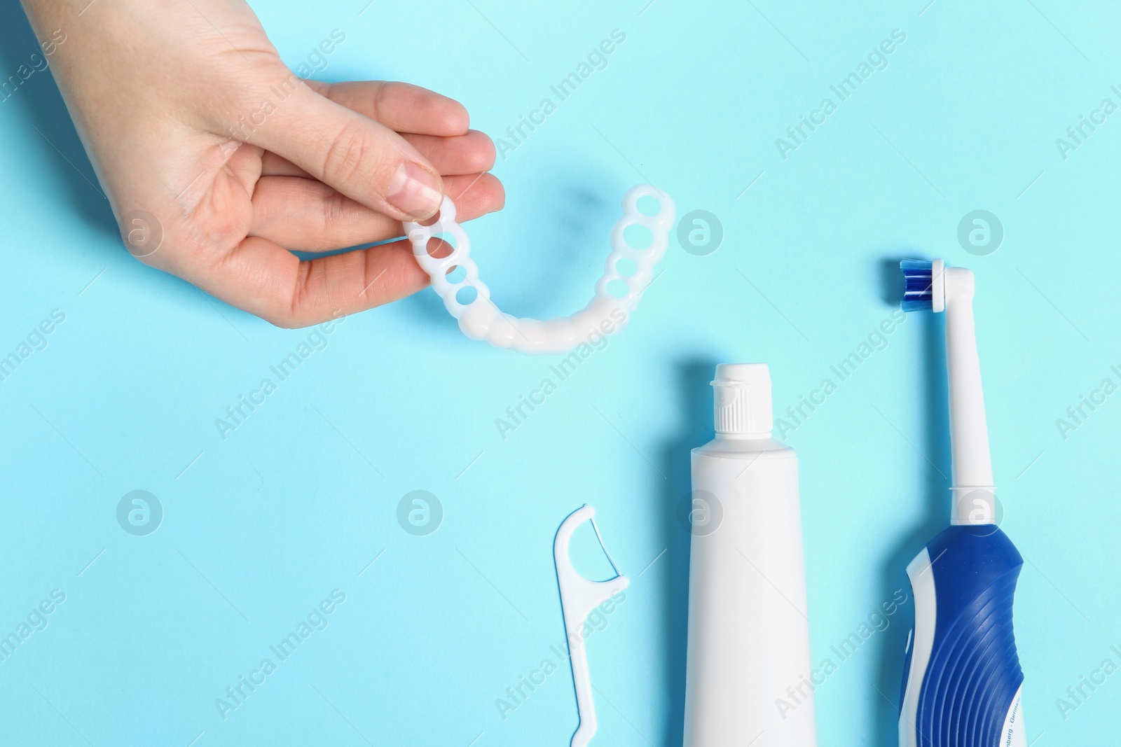 Photo of Woman with teeth cover and oral care products on color background, top view