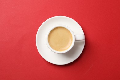 Photo of Aromatic coffee in cup on red background, top view