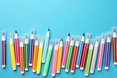 Photo of Many bright markers on light blue background, flat lay. Space for text