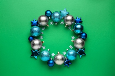 Photo of Beautiful festive wreath made of different Christmas balls on green background, top view