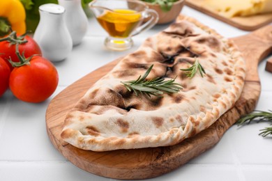 Tasty pizza calzone with rosemary and different products on white table, closeup