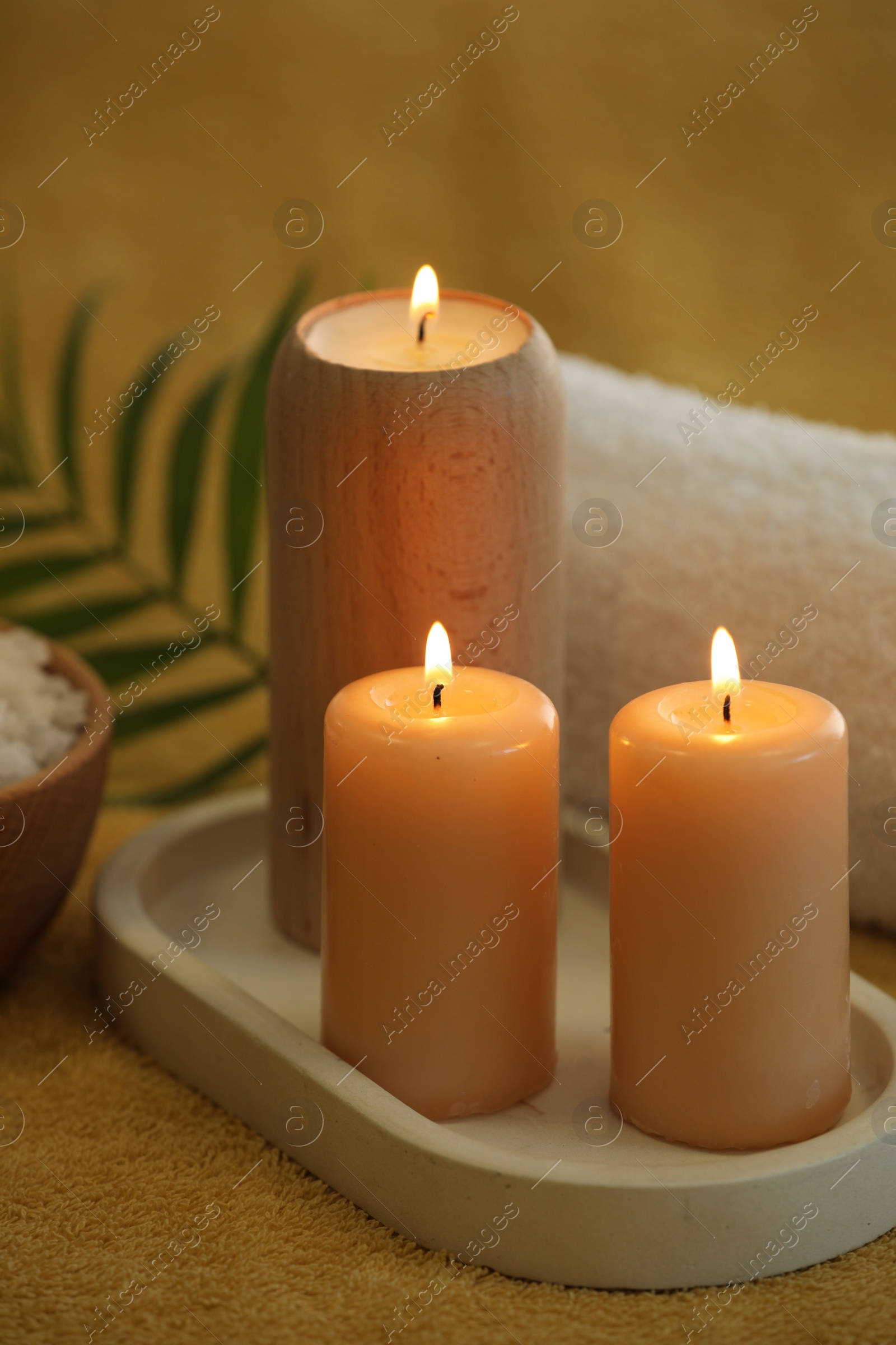 Photo of Spa composition with burning candles on soft yellow fabric