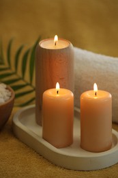 Photo of Spa composition with burning candles on soft yellow fabric