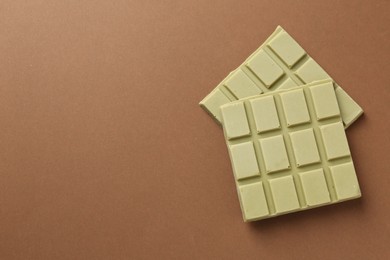 Photo of Pieces of tasty matcha chocolate bar on brown background, top view. Space for text