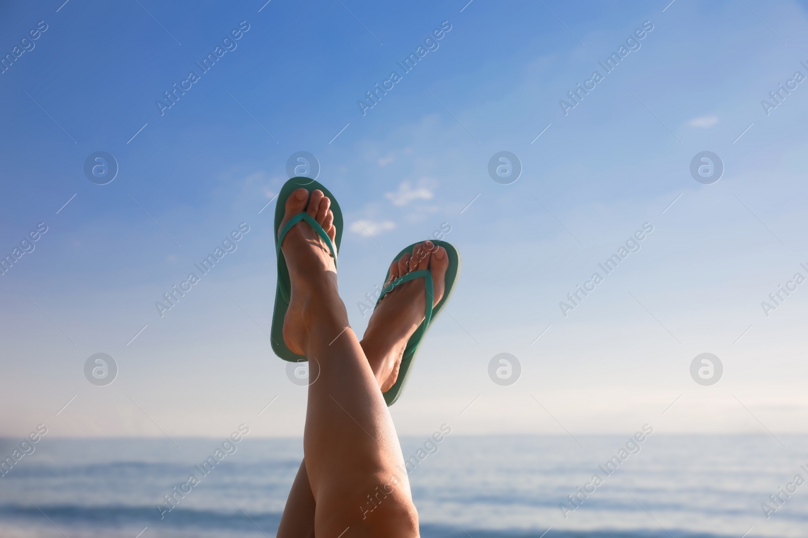 Photo of Woman in stylish flip flops near sea, closeup