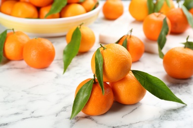 Photo of Fresh tangerines with green leaves on white marble table