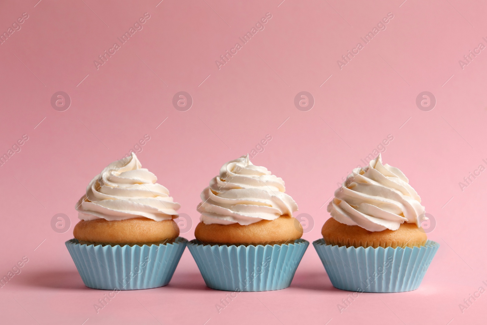 Photo of Delicious cupcakes decorated with cream on pink background