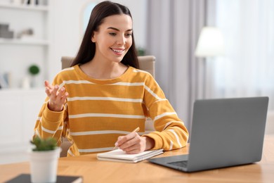 Photo of Young woman using video chat during webinar at table in room