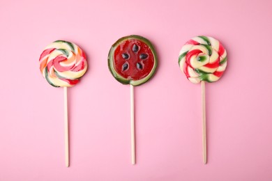 Photo of Different colorful lollipops on pink background, flat lay