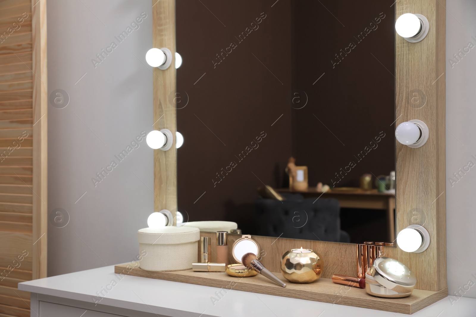 Photo of Stylish dressing table with cosmetics, mirror and accessories near white wall