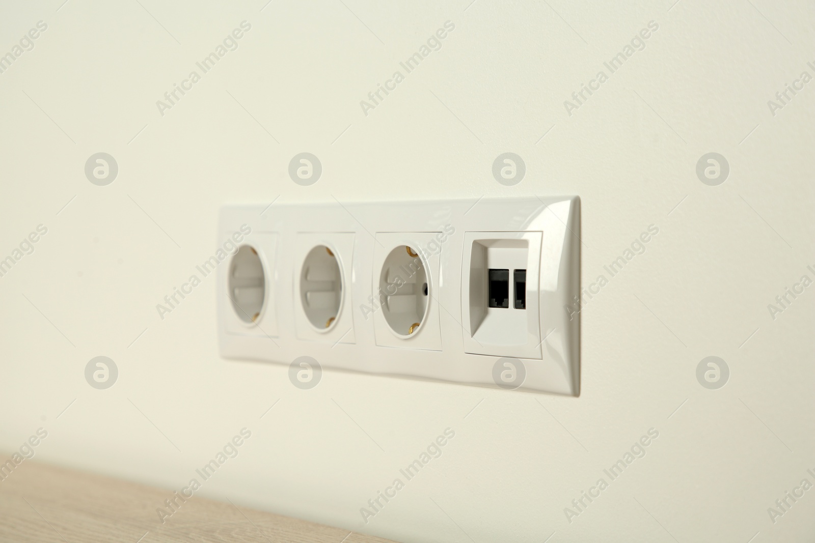 Photo of Many power sockets with ethernet plate on white wall indoors