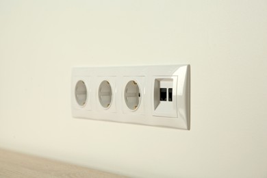 Many power sockets with ethernet plate on white wall indoors