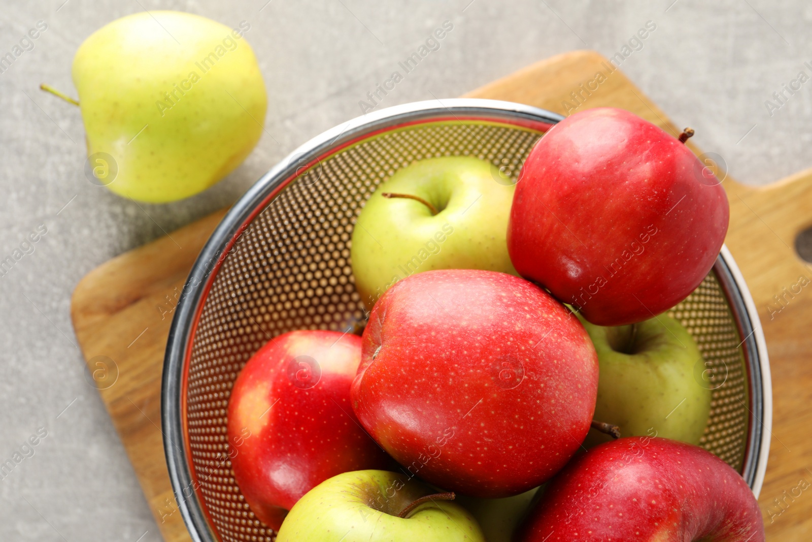 Photo of Fresh ripe apples in colander on light grey table, top view