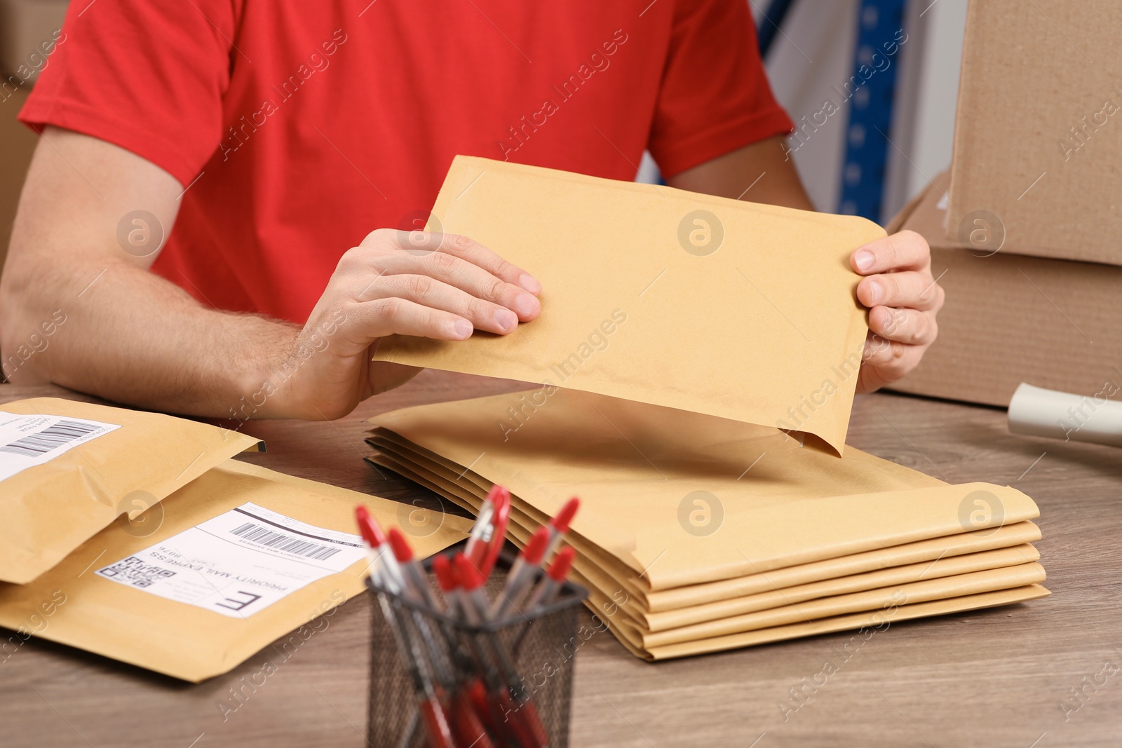 Photo of Post office worker with adhesive paper bags at counter indoors, closeup