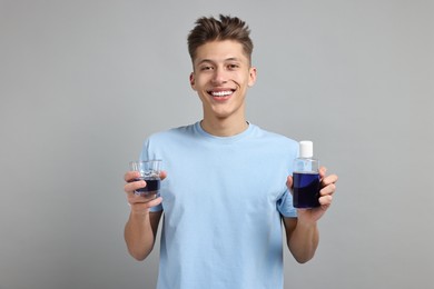 Young man with mouthwash on light grey background