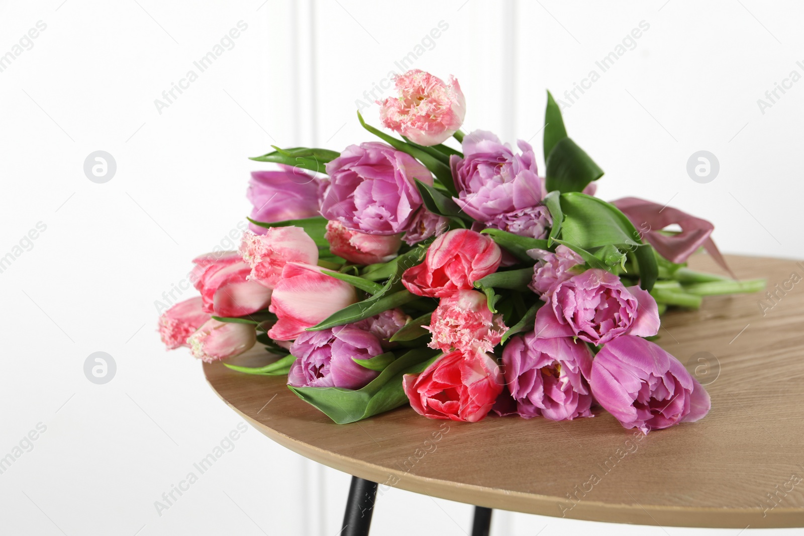 Photo of Beautiful bouquet of colorful tulip flowers on wooden table