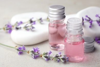 Photo of Bottles with natural lavender essential oil on light background. Space for text