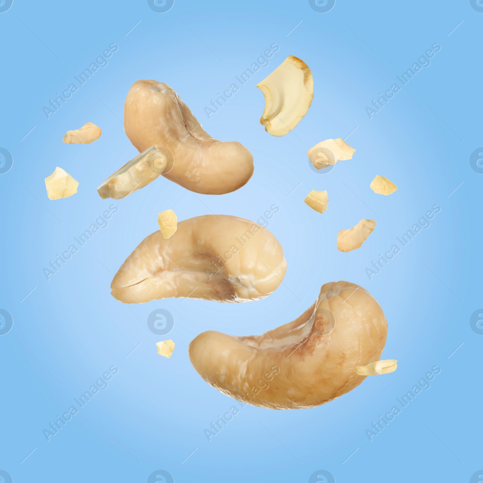 Image of Tasty cashew nuts flying on light blue background