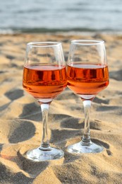 Photo of Glassestasty rose wine on sand near sea