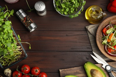 Photo of Frame of different ingredients and fresh organic microgreen on wooden table, flat lay. Space for text