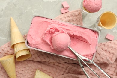Photo of Delicious ice cream in container and wafer cones on light grey table, flat lay