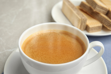 Delicious coffee and wafers for breakfast on grey table, closeup