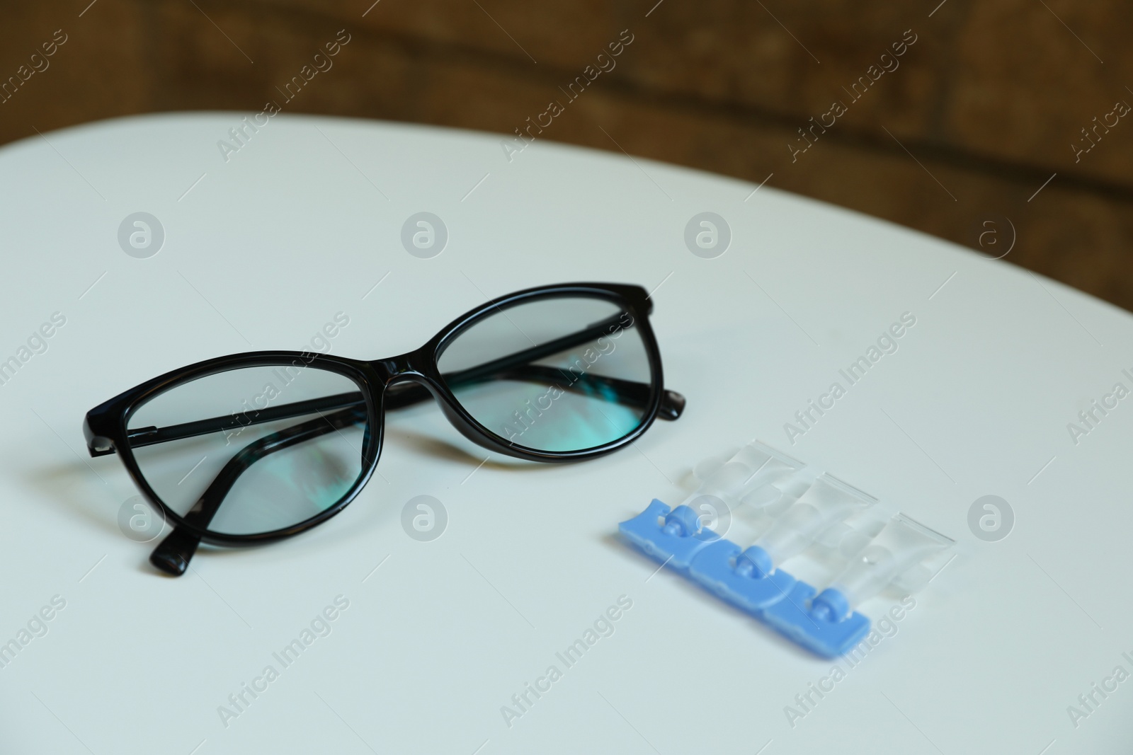 Photo of Single dose eye drops and glasses on white table