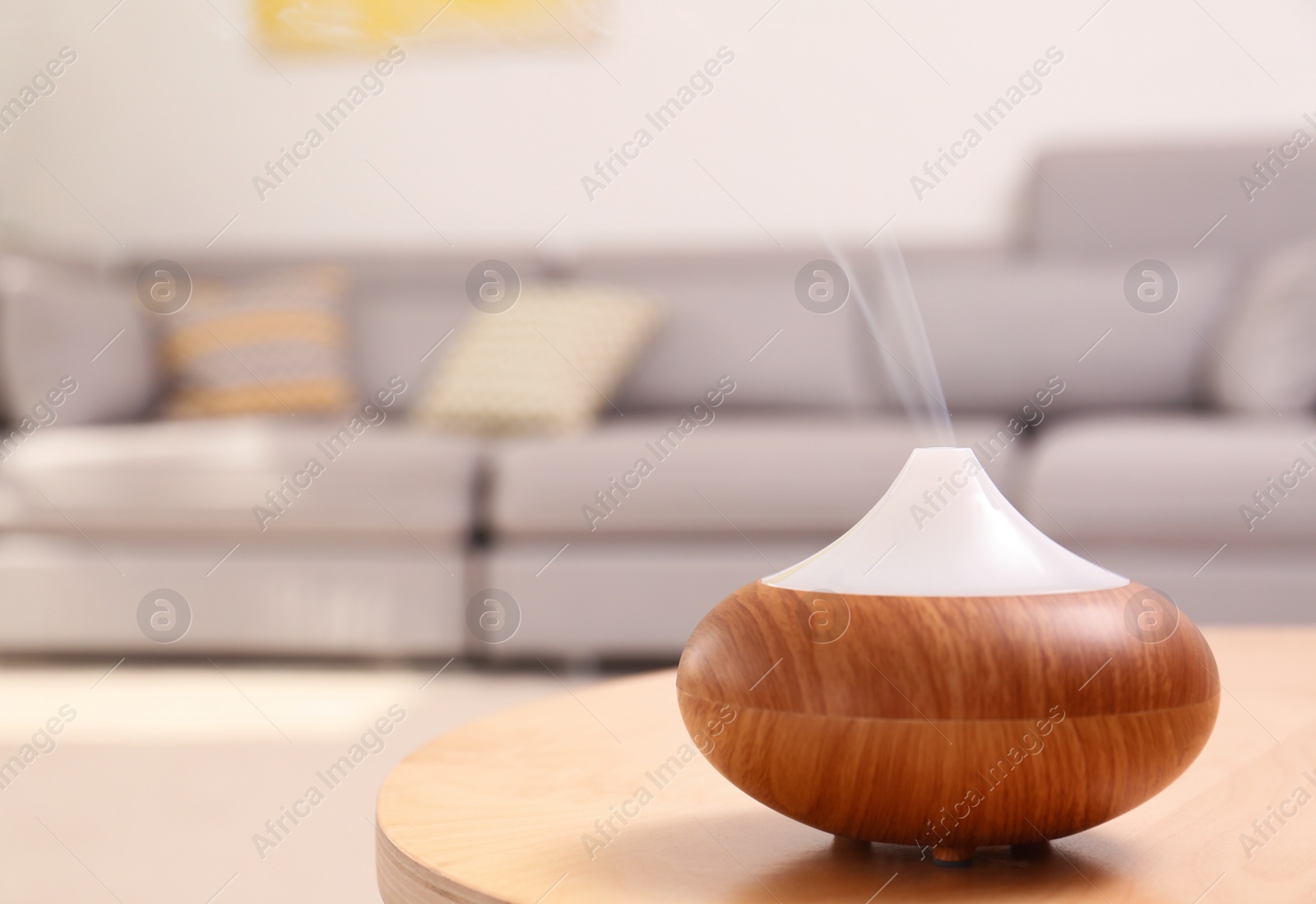 Photo of Modern essential oil diffuser on table in room. Space for text