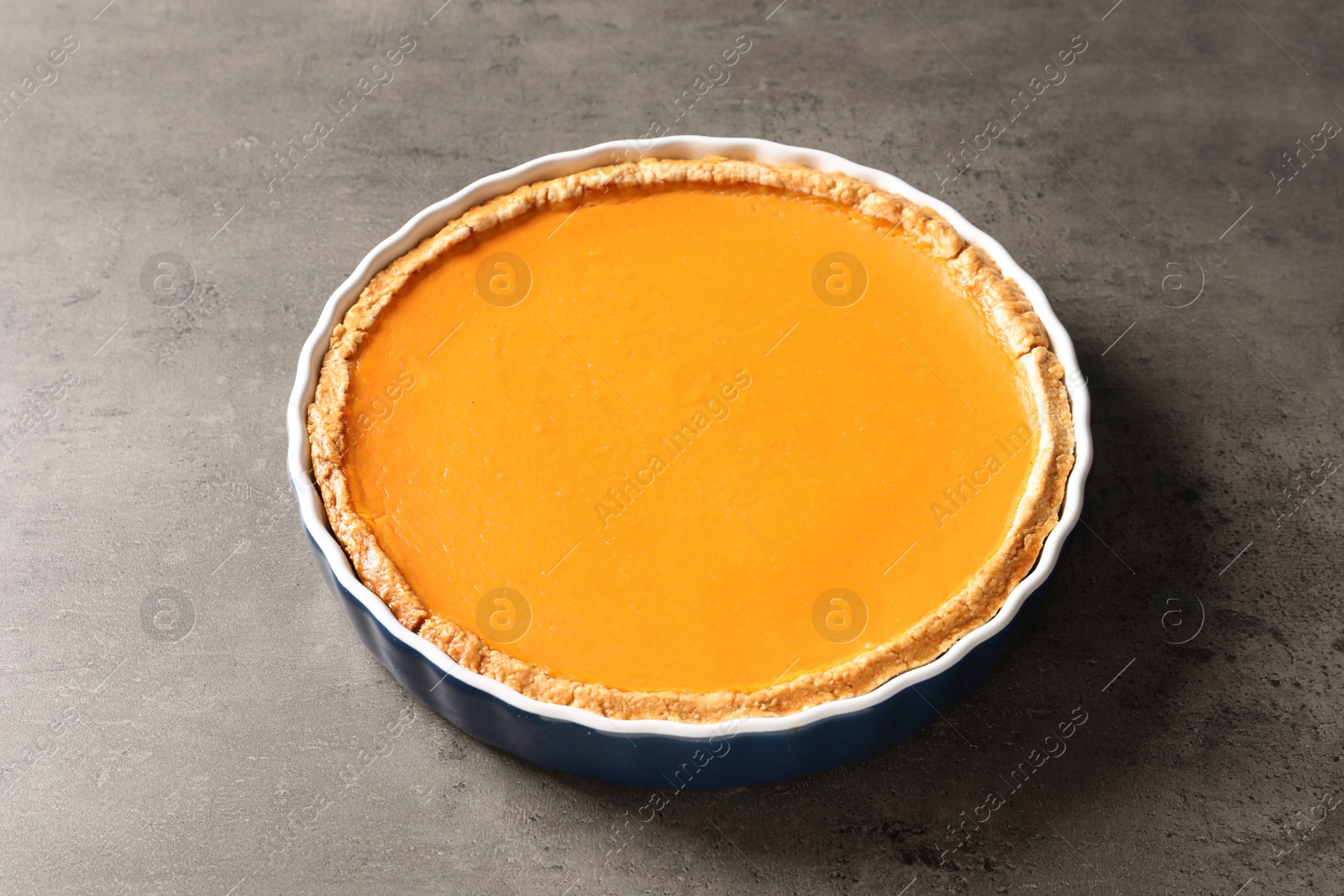 Photo of Fresh delicious homemade pumpkin pie on gray background