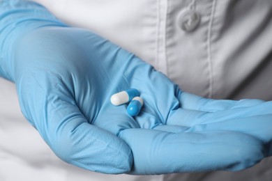 Photo of Doctor in medical glove holding pills, closeup view