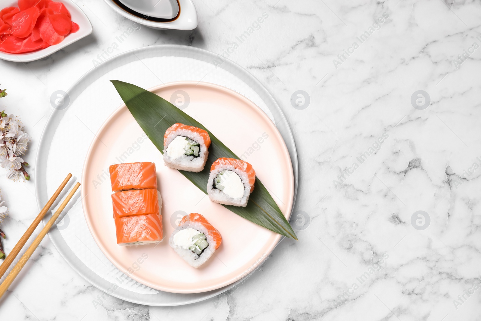Photo of Tasty sushi rolls, soy sauce and ginger on white marble table, flat lay