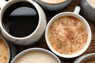 Photo of Many cups of different coffees on wooden table, flat lay