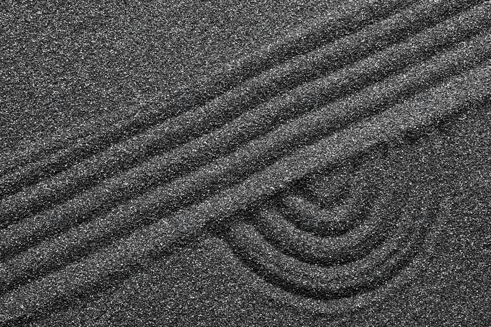 Photo of Pattern on decorative black sand, top view. Zen and harmony