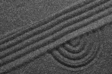 Photo of Pattern on decorative black sand, top view. Zen and harmony