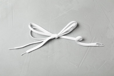 Photo of White shoelaces on light grey stone background, top view