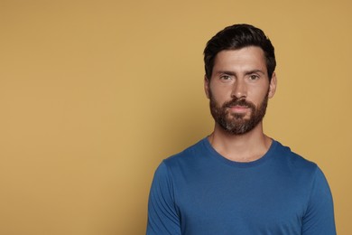 Portrait of handsome bearded man on yellow background, space for text
