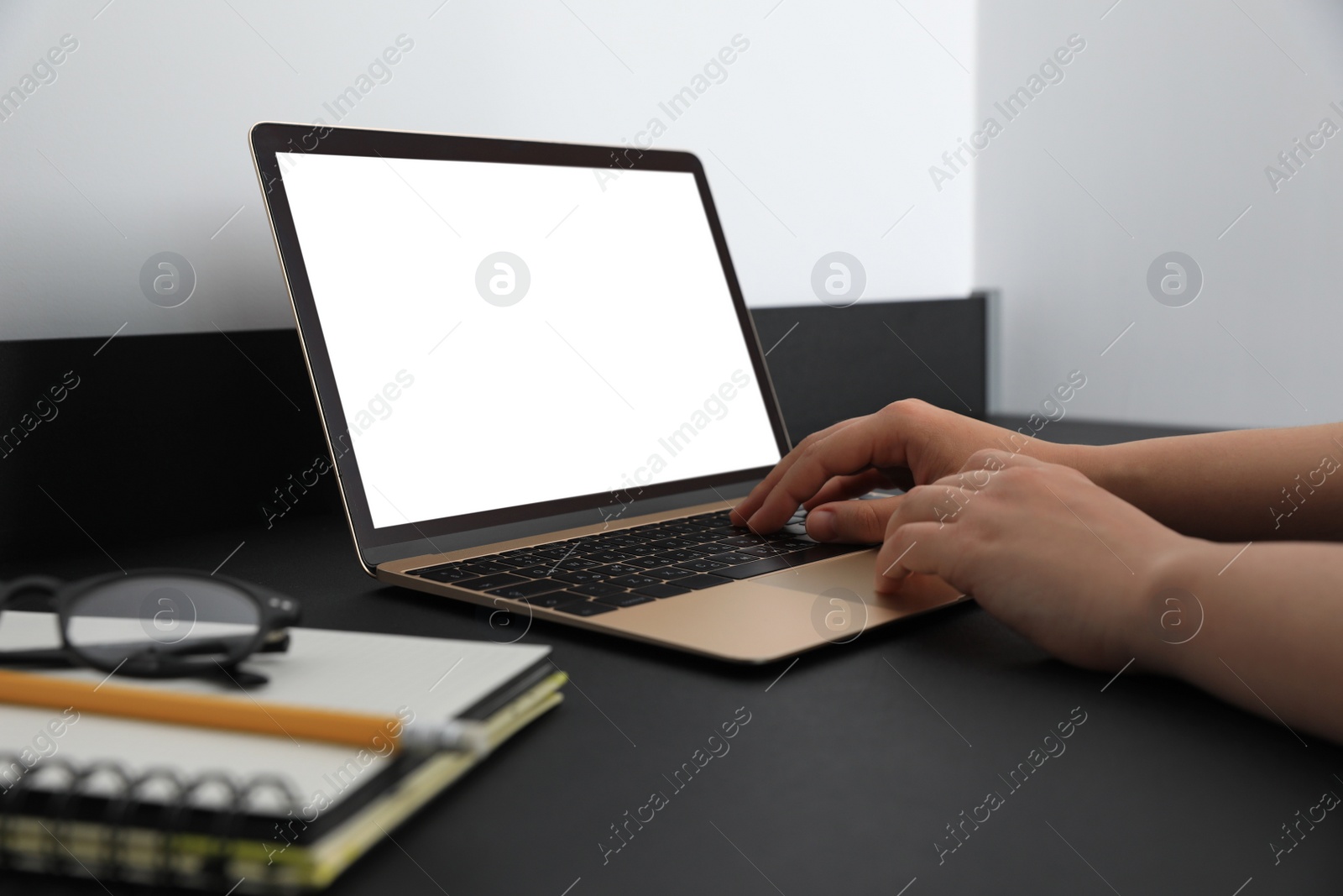 Photo of Woman working on modern laptop at black table, closeup. Space for design