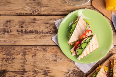 Photo of Green plate with tasty sandwiches on wooden table, flat lay. Space for text